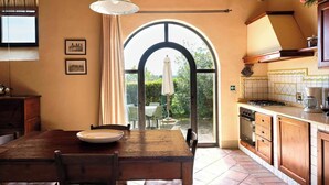 A kitchen with a large window, wooden cabinets, and a dining table with chairs. - Glicini 1, holiday home with pool 30' from Florence (Barberino Tavarnelle)