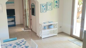 Ein geräumiges Zimmer mit einem Esstisch, einem weißen Schrank und Fischbildern in Rahmen.