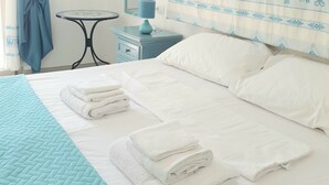 A neatly made bed with white linens and folded towels, a small table with a lamp, and a blue curtain. - Villa Lentischio at 100 m to the sea with private garden,wif,airco,parking,bbq (Budoni)