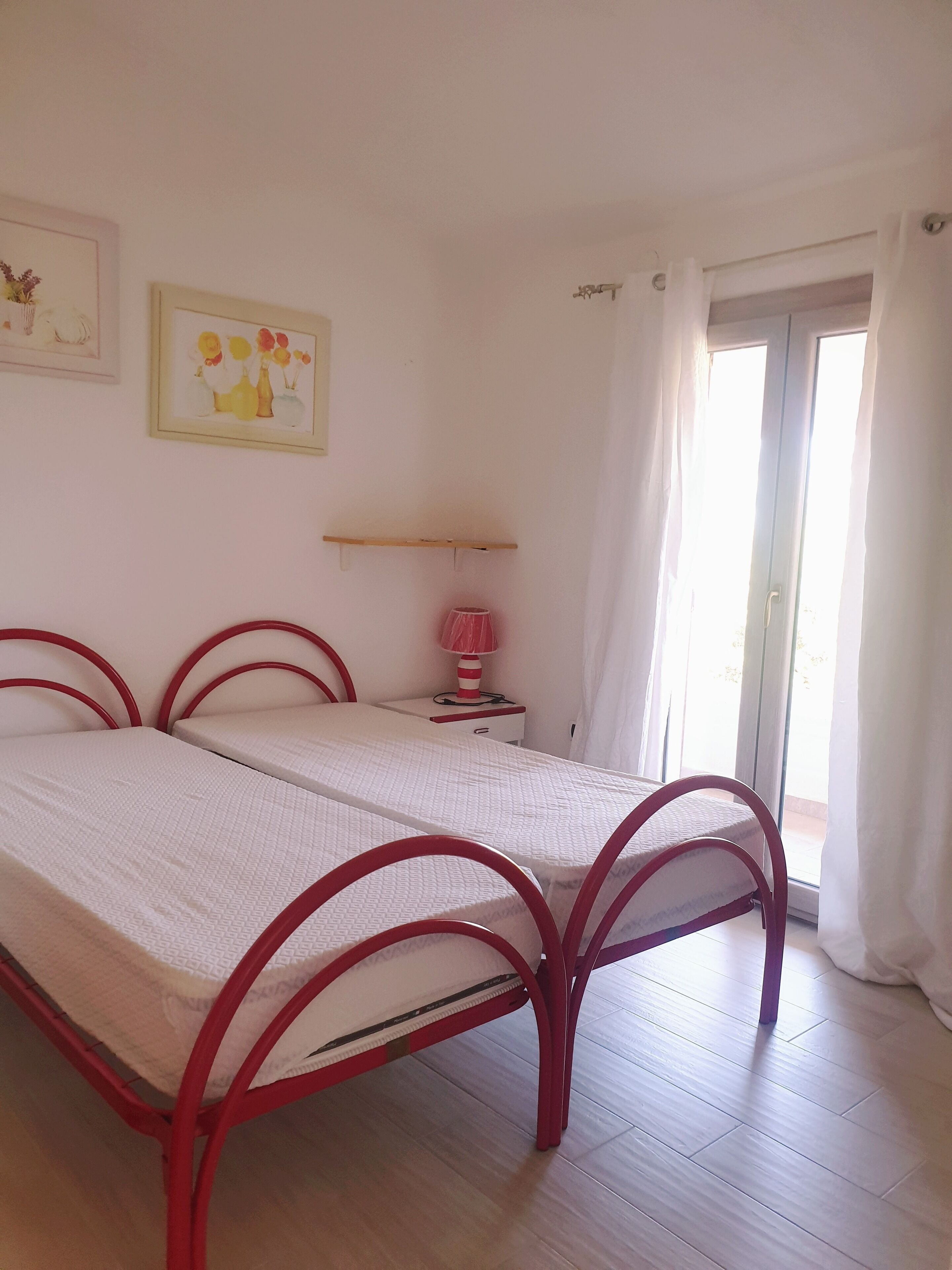 Une chambre à coucher comprenant un lit, une table de chevet, une lampe et deux tableaux accrochés au mur.