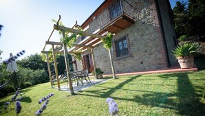 Un bâtiment en pierre doté d’une pergola en bois et d’un patio aménagé avec du mobilier d’extérieur.