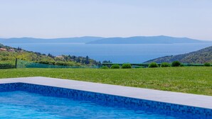 Piscina amb vistes a una massa d'aigua i a les colines de la distància.