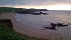 A coastal landscape with a sandy beach, grassy areas, and a rocky outcrop in the sea. - House With Sea Views And Sunny Aspect (Thurlestone)