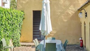 A courtyard with a table and chairs, a covered umbrella, and a fire extinguisher.
