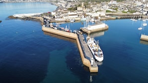 A coastal town with a harbor, including a large ship docked at the pier and a bridge connecting the town to the mainland. - Delightful quiet space, very close to the town & promenade.  (Penzance)