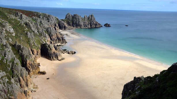 A coastal landscape with a sandy beach, rocky cliffs, and calm sea. - Delightful quiet space, very close to the town & promenade.  (Penzance)