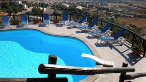 A swimming pool with lounge chairs and a view of a coastal town. - Two-room apartment with sea view, swimming pool and relax (Porto San Paolo)