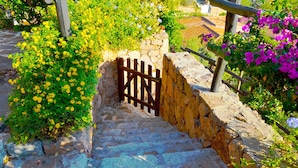 A stone staircase with a wooden gate leading to a stone wall. - Two-room apartment with sea view, swimming pool and relax (Porto San Paolo)