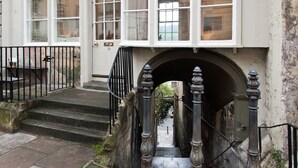Un bâtiment doté d’un escalier en pierre menant à une porte, d’une petite arche et d’une rambarde en métal noir.