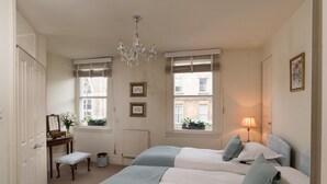 Une chambre avec deux lits, une commode, une coiffeuse et un lustre.