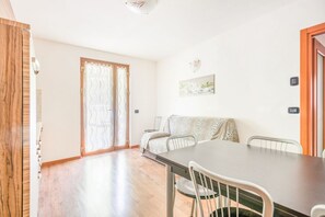 Una habitación con piso de madera, una mesa de comedor con sillas, un sofá con estampado de leopardo, un cerrojo corredizo de vidrio y un aplique de pared.