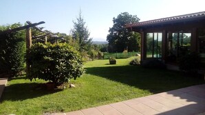 A well-maintained garden with a patio area, a pergola, and a view of the surrounding landscape. - Anxeliña House - HB001 (BOBORAS ,OURENSE)