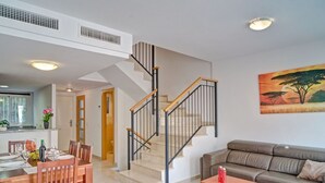 A modern living room with a staircase, a dining area, and a sofa. - Cosy apartment for 6 people with A/C, pool, WIFI, TV and terrace (Calpe)