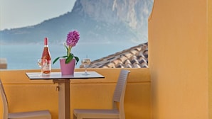 A table with a bottle of wine, a glass, and a potted flower, overlooking a mountainous landscape. - Cosy apartment for 6 people with A/C, pool, WIFI, TV and terrace (Calpe)