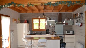 A kitchen with wooden beams, a white refrigerator, a microwave, and a sink.