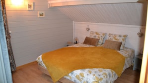 A bedroom with a sloped ceiling, a bed with floral bedding, and a yellow throw blanket.