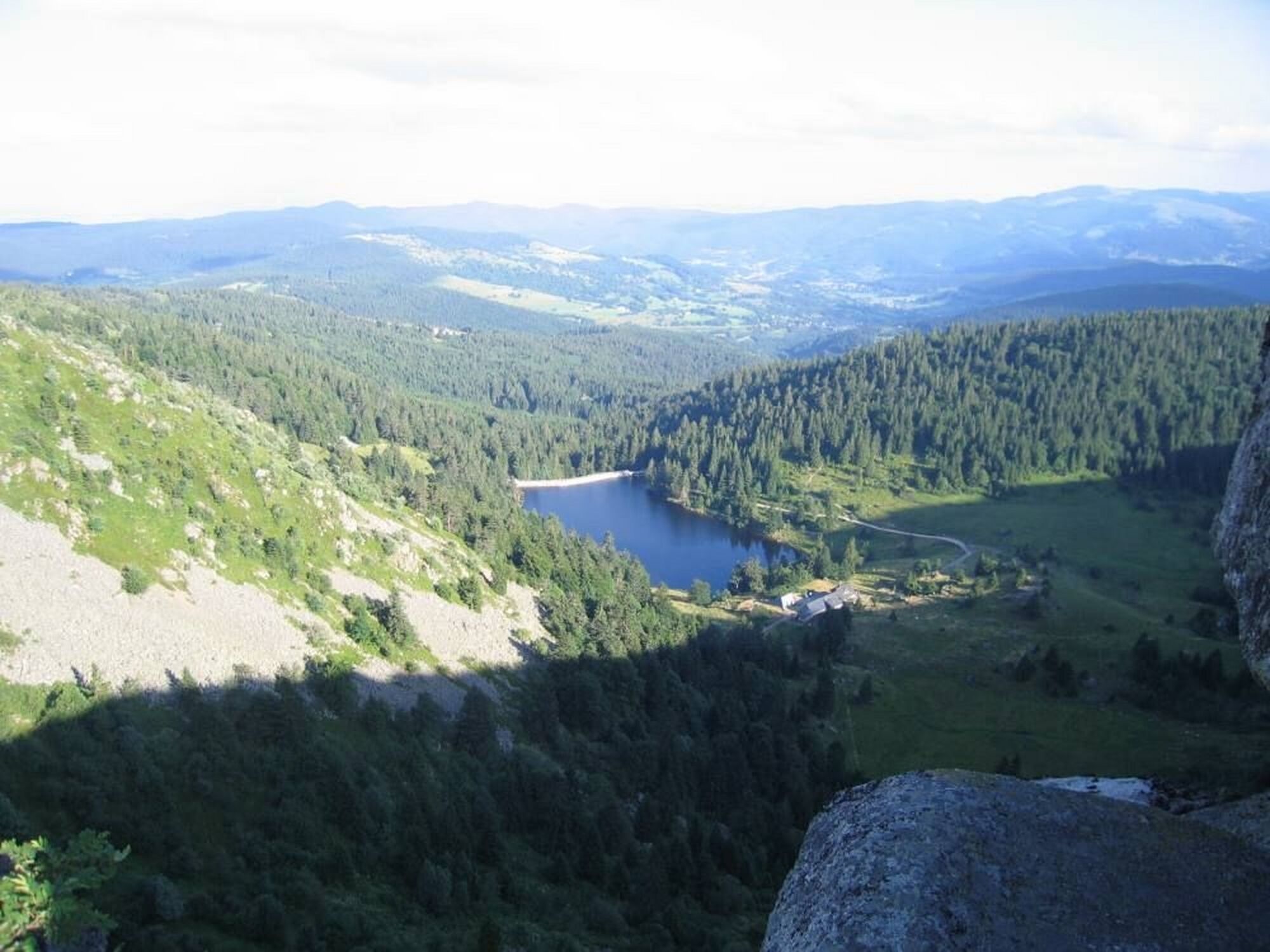 Een bergachtig landschap met een meer, beboste gebieden en een heldere lucht.