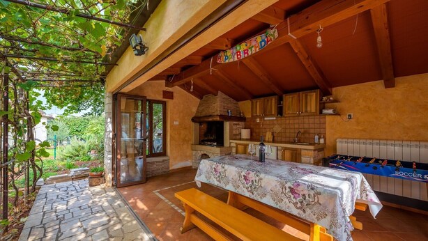 A cozy outdoor dining area with a table set for two, a wooden bench, and a foosball table. - ALEKS house with apartments / Aleks 2 APARTMENT (Umag)