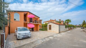 A white car parked in front of a house with a balcony and a stone wall. - ALEKS house with apartments / Aleks 2 APARTMENT (Umag)