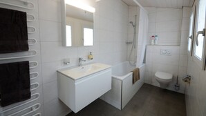 A modern bathroom with a white sink, mirror, and bathtub. - Stylish new apartment located 3 mins walk from Interlaken West station. (Interlaken)