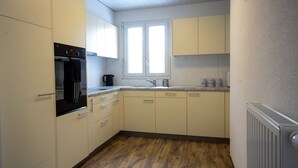 A compact kitchen with white cabinets, a built-in oven, and a window above the sink. - Stylish new apartment located 3 mins walk from Interlaken West station. (Interlaken)