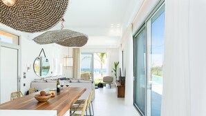 Een moderne keuken met een houten kookeiland, grote ramen en uitzicht op zee.