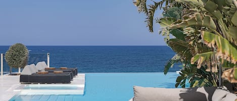 A poolside area with lounge chairs and a view of the sea.