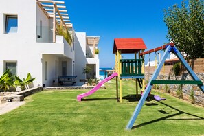 A modern house with a white exterior, a balcony, and a small patio area with a table and chairs. - La Casa di Mare, Luxury SeaFront Villa with Private Pool, Whirlpools & Sauna (Rethymno)