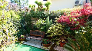 Ein Garten mit einer hölzernen Bank, Blumentöpfen und einem kleinen Teich.
