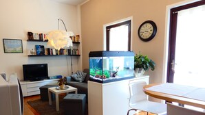Ein Wohnzimmer mit Fernseher, Sofa, Couchtisch und einem Aquarium.