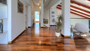Un hall d’entrée spacieux, doté d’un plancher en bois, de murs blancs et d’un plafond avec des poutres apparentes.