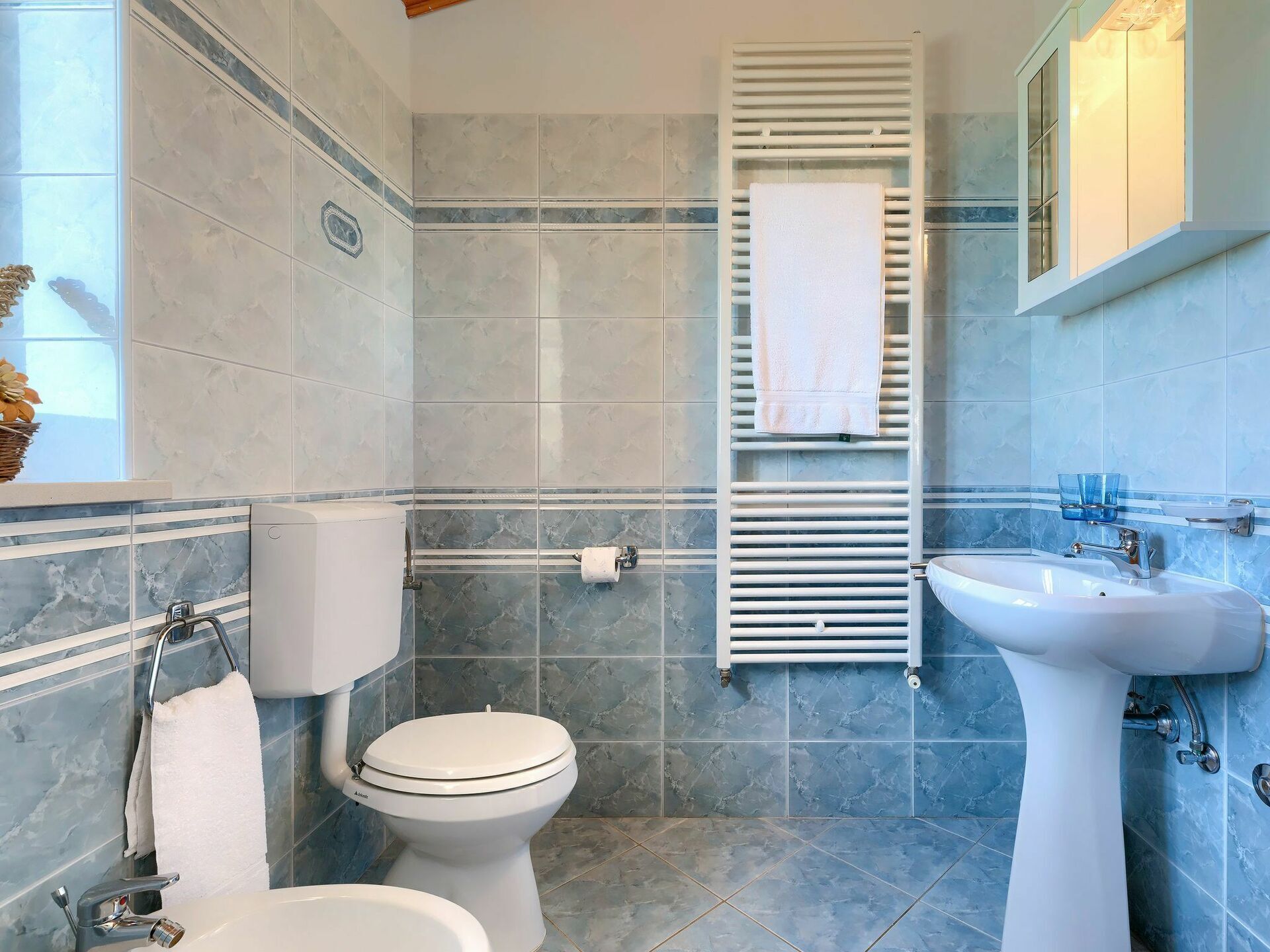 A bathroom with a toilet, bidet, and sink, all with modern fixtures.