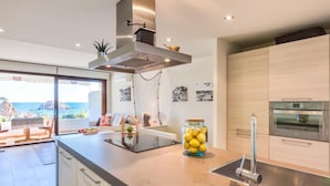 Een moderne keuken met een groot kookeiland, roestvrijstalen apparatuur en uitzicht op de oceaan.