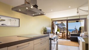 Een moderne keuken met een groot eiland, een eetgedeelte met uitzicht en een woonruimte met een bank en tafel.