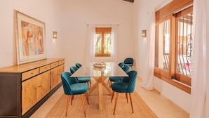 A dining area with a glass-top table surrounded by six chairs, a wooden cabinet, and a large painting on the wall. - Mirador, A Luxury villa rental - cliff top retreat with breathtaking views      (Xàbia)