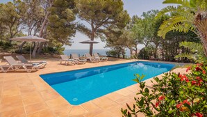 A swimming pool with sun loungers and umbrellas, surrounded by trees and a view of the sea. - Mirador, A Luxury villa rental - cliff top retreat with breathtaking views      (Xàbia)