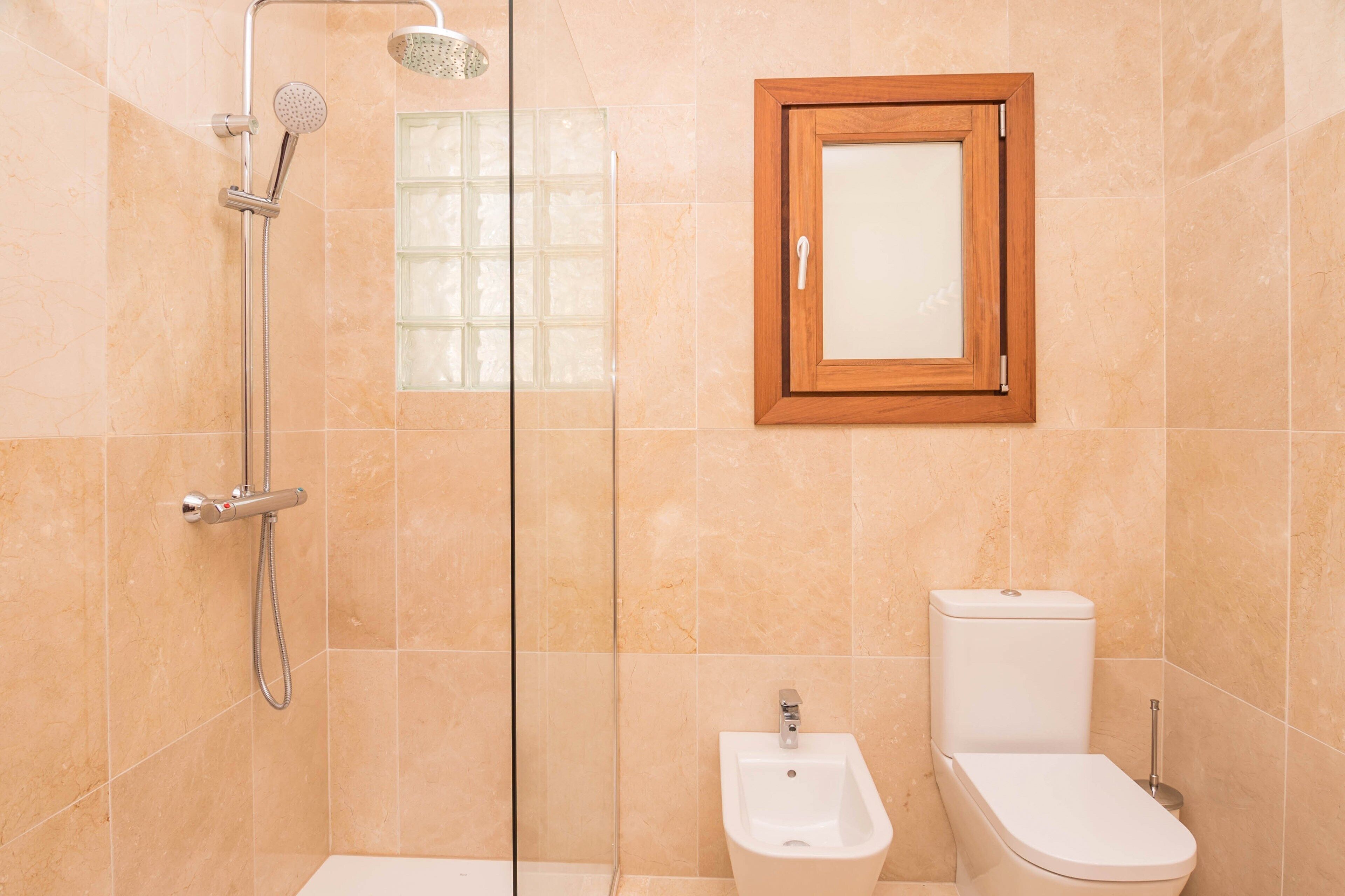 Ein Badezimmer mit Dusche, Bidet, Toilette und einem gerahmten Spiegel an der Wand.