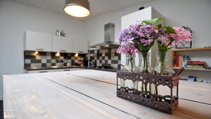A kitchen with a white countertop, a decorative vase with purple flowers, and a checkered backsplash.