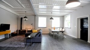 A modern living room with a sofa, TV, and dining area.
