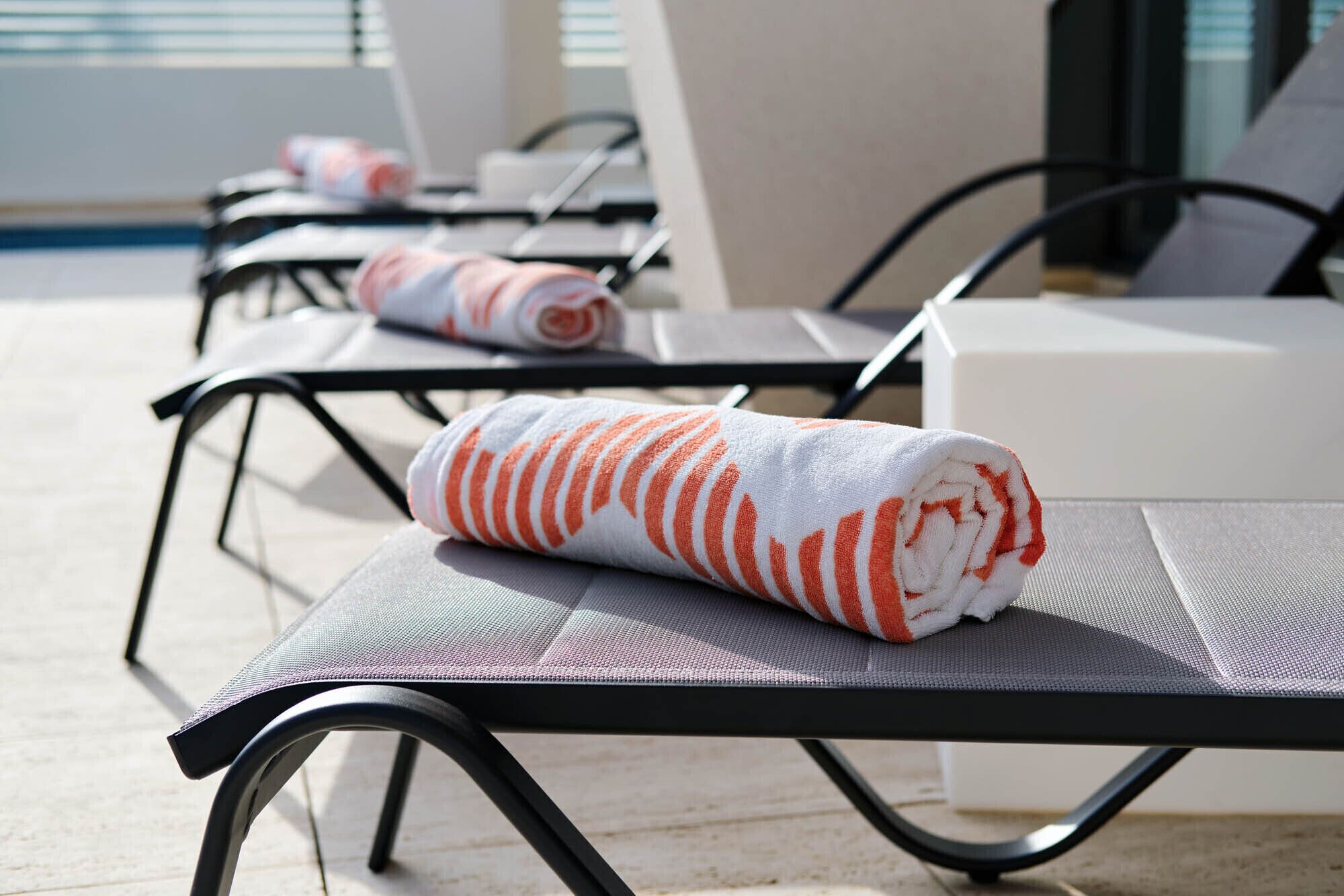 Un espace aménagé au bord de la piscine, avec des chaises longues et une serviette posée sur l’une d’elles.