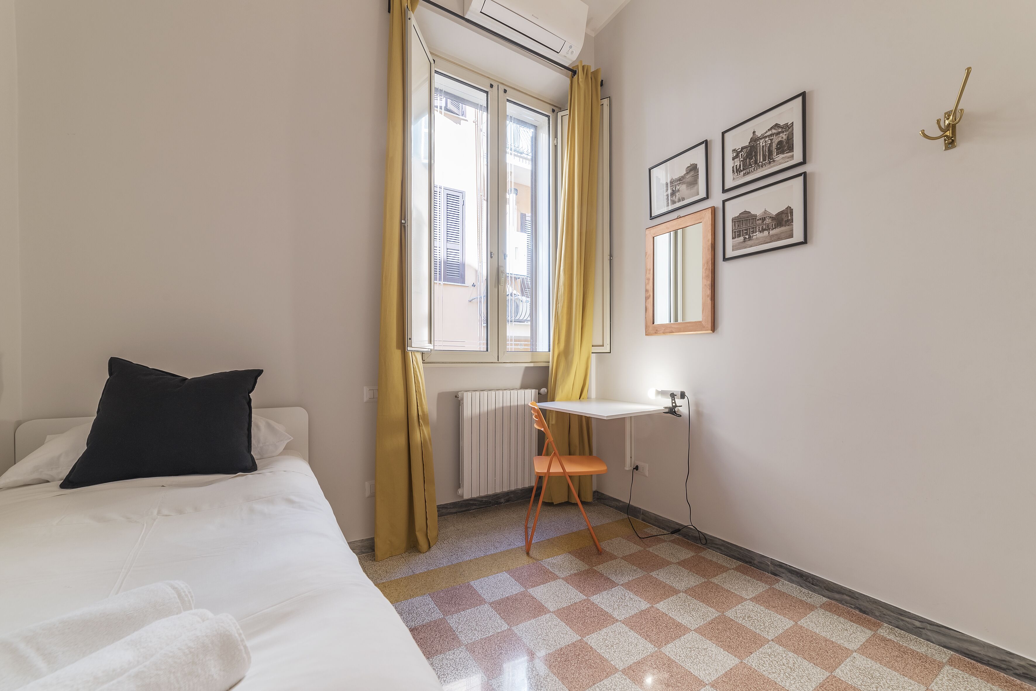 Un dormitorio con cama, escritorio, silla y radiador.