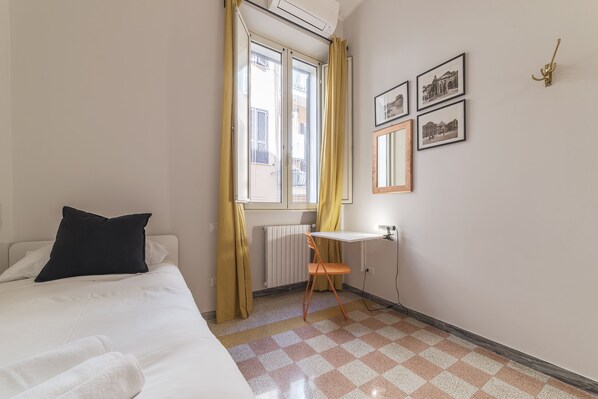Une chambre à coucher avec un lit, un bureau, une chaise et un radiateur.