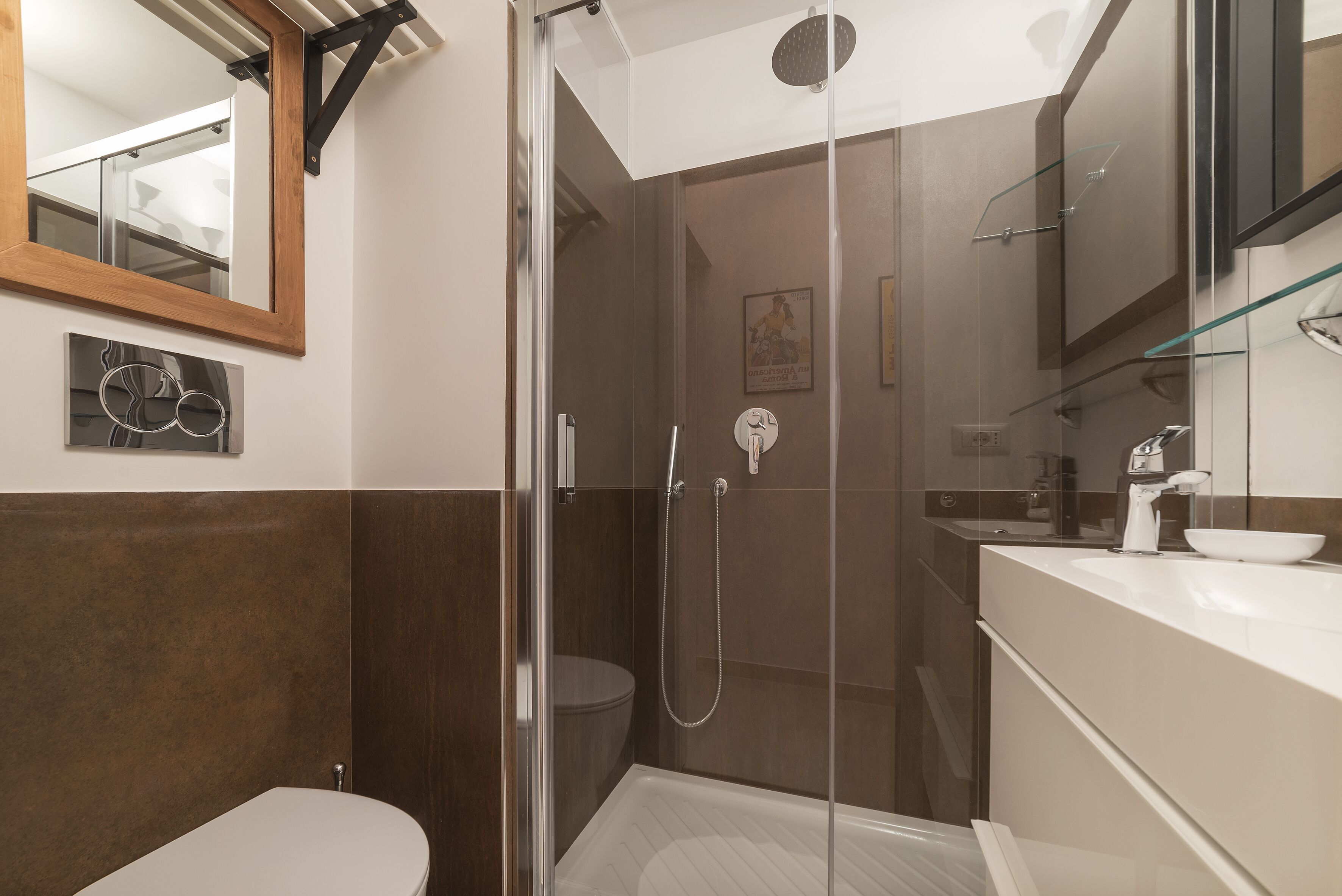A modern bathroom with a glass shower enclosure, a toilet, and a sink with a mirror above.