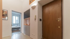 A hallway with a wooden door, a light switch, and a wall-mounted light fixture.