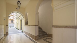 A corridor with a marble floor, a staircase, and a decorative archway.