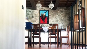 A dining area with a wooden table and chairs, a stone wall, and a staircase leading to another level. - ✨ Luxury Tuscan Villa | Private Pool, BBQ, Wood Oven | Helicopter Tours Nearby (san romano di garfagnana (LU))