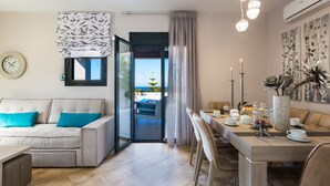 Een moderne woonkamer met een bank, een eettafel en uitzicht op de omgeving.