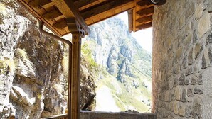 A wooden balcony with stone walls, a table, and two chairs. - The Caleyon, village house with breakfast. Rooms with private bathroom. (Bulnes de Cabrales)