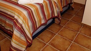 A double bed with striped bedding and two towels, a window with a view of trees, and a tiled floor. - The Caleyon, village house with breakfast. Rooms with private bathroom. (Bulnes de Cabrales)