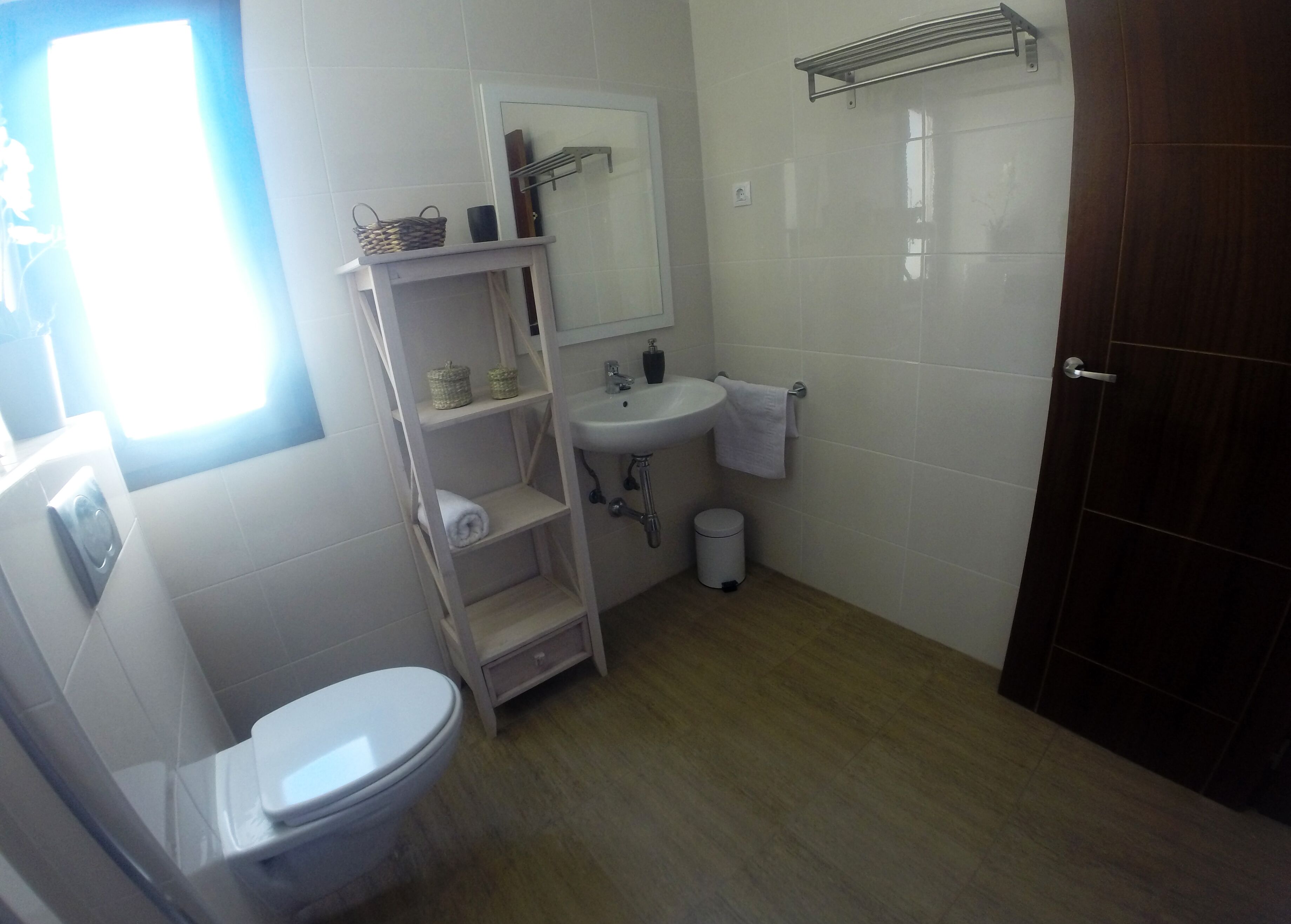 Une salle de bain comprenant des toilettes, un lavabo, des étagères avec des paniers et un porte-serviettes.
